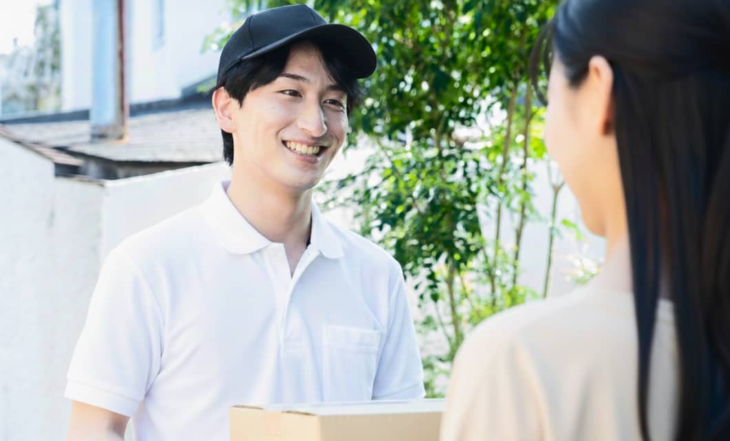 関先で笑顔で荷物を受け渡す配達員の男性とお客様